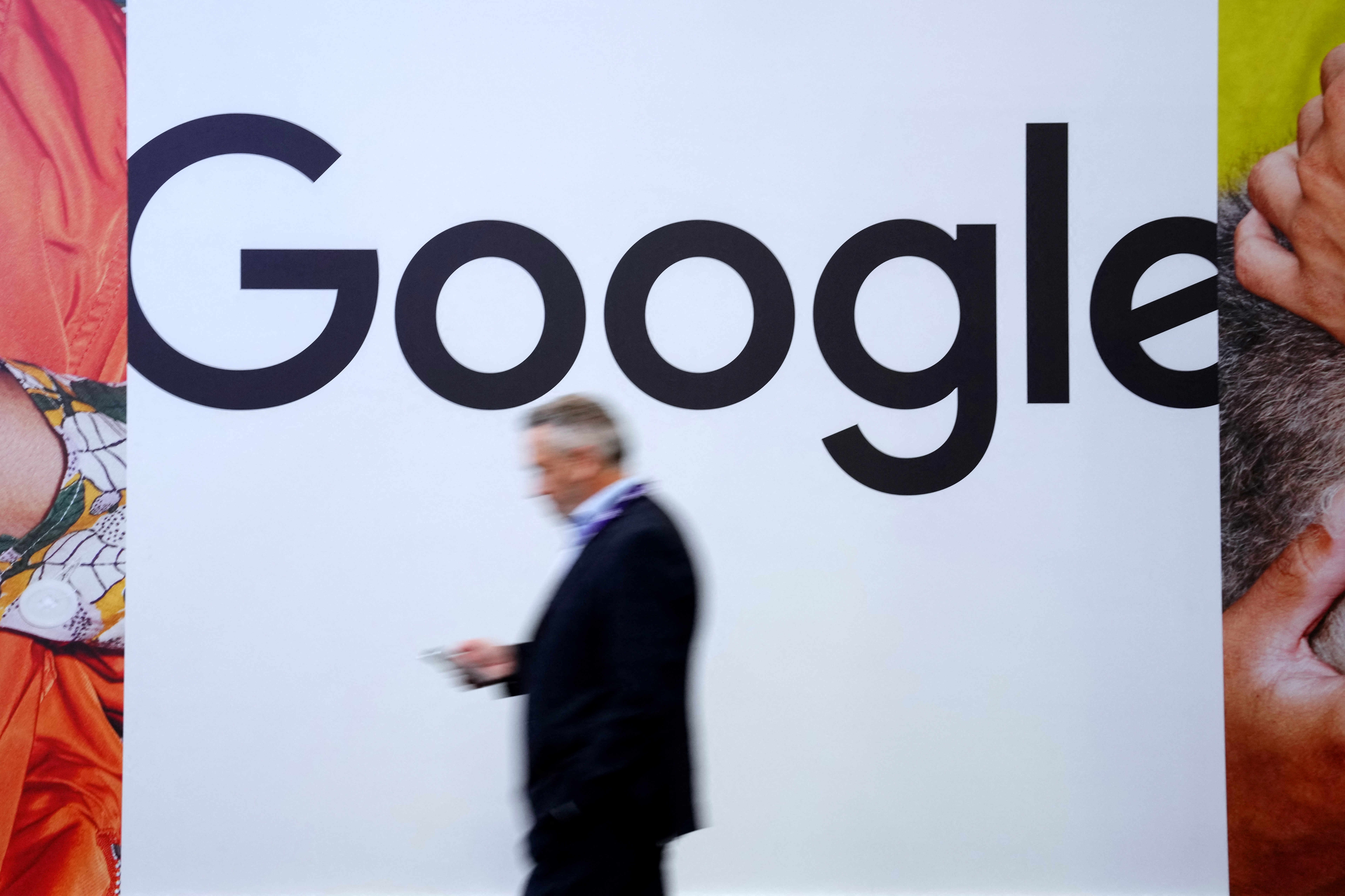 A man walks past a large Google logo.